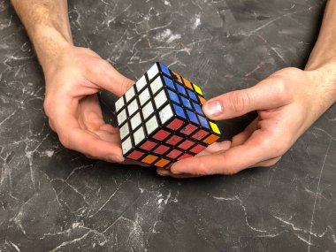 Rubik küpü 3 x 3 erkek eller, yakın çekim, üstten görünüm, mermer arka plan.