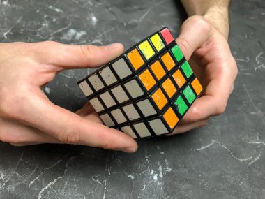 Rubik küpü 3 x 3 erkek eller, yakın çekim, üstten görünüm, mermer arka plan.