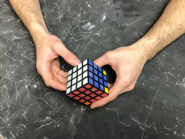 Rubik küpü 3 x 3 erkek eller, yakın çekim, üstten görünüm, mermer arka plan.