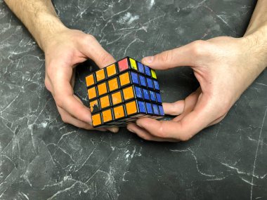 Rubik küpü 3 x 3 erkek eller, yakın çekim, üstten görünüm, mermer arka plan.