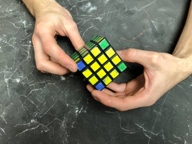 Rubik küpü 3 x 3 erkek eller, yakın çekim, üstten görünüm, mermer arka plan.