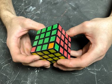 Rubik küpü 3 x 3 erkek eller, yakın çekim, üstten görünüm, mermer arka plan.