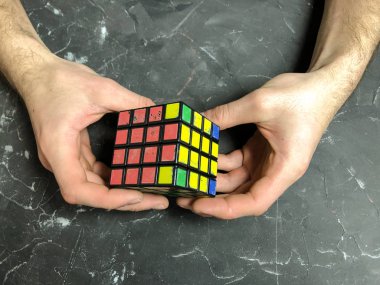 Rubik küpü 3 x 3 erkek eller, yakın çekim, üstten görünüm, mermer arka plan.