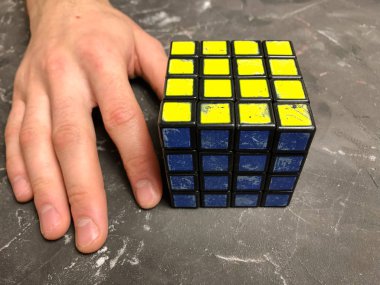 Rubik küpü 3 x 3 erkek eller, yakın çekim, üstten görünüm, mermer arka plan.