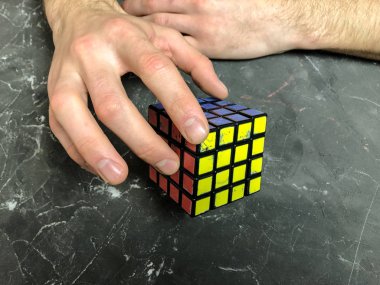 Rubik küpü 3 x 3 erkek eller, yakın çekim, üstten görünüm, mermer arka plan.