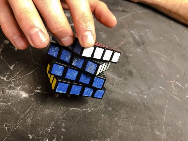 Rubik küpü 3 x 3 erkek eller, yakın çekim, üstten görünüm, mermer arka plan.