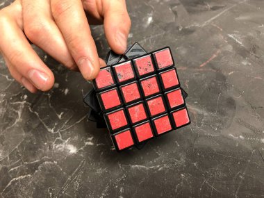 Rubik küpü 3 x 3 erkek eller, yakın çekim, üstten görünüm, mermer arka plan.