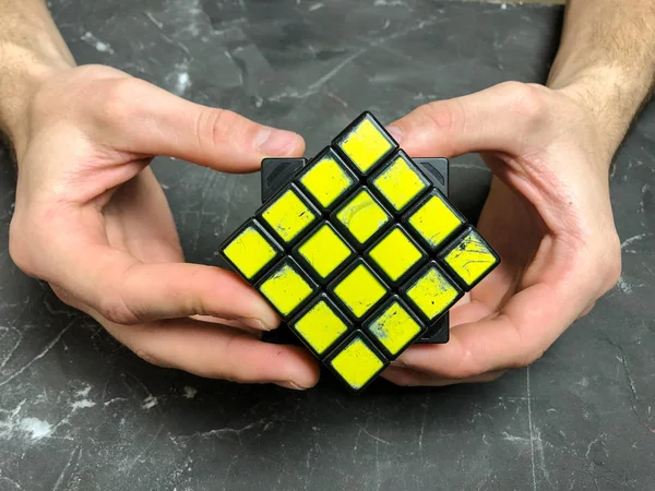 Rubik küpü 3 x 3 erkek eller, yakın çekim, üstten görünüm, mermer arka plan.