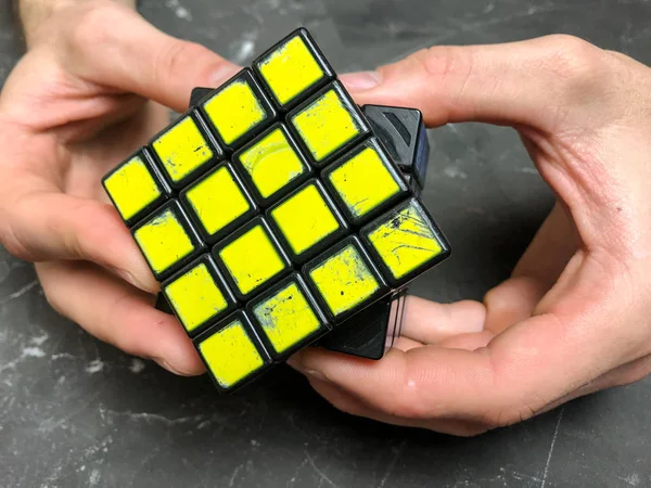 Rubik küpü 3 x 3 erkek eller, yakın çekim, üstten görünüm, mermer arka plan.