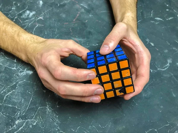 Rubik küpü 3 x 3 erkek eller, yakın çekim, üstten görünüm, mermer arka plan.