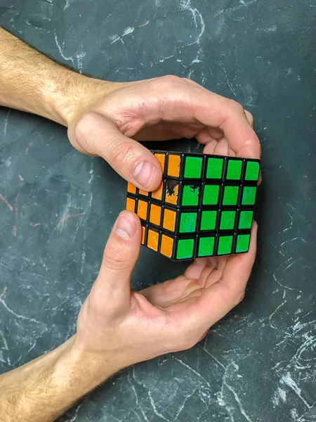 Rubik küpü 3 x 3 erkek eller, yakın çekim, üstten görünüm, mermer arka plan.