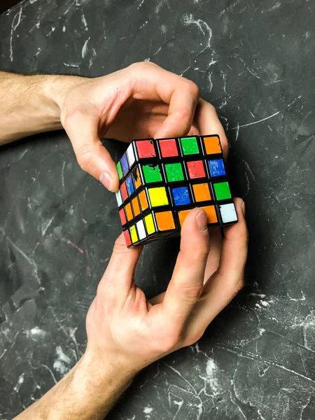 Rubik küpü 3 x 3 erkek eller, yakın çekim, üstten görünüm, mermer arka plan.
