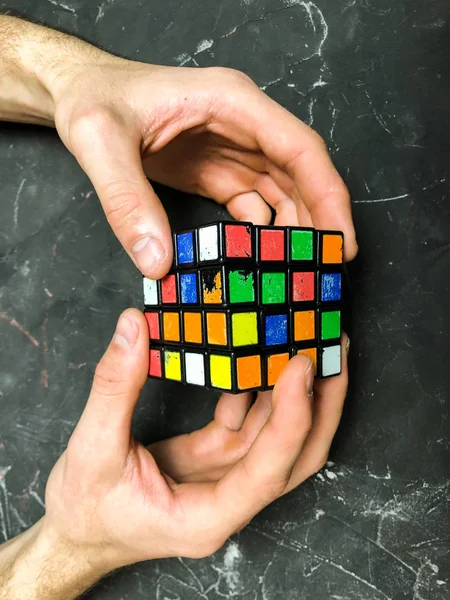 Rubik küpü 3 x 3 erkek eller, yakın çekim, üstten görünüm, mermer arka plan.