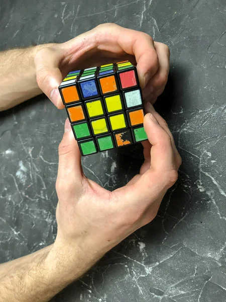 Rubik küpü 3 x 3 erkek eller, yakın çekim, üstten görünüm, mermer arka plan.