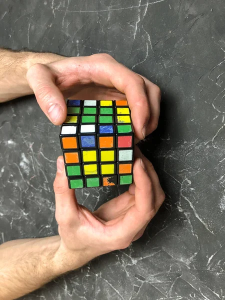Rubik küpü 3 x 3 erkek eller, yakın çekim, üstten görünüm, mermer arka plan.