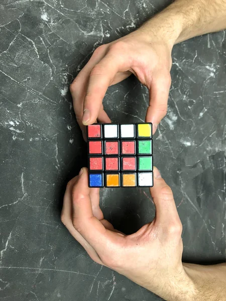 Rubik küpü 3 x 3 erkek eller, yakın çekim, üstten görünüm, mermer arka plan.