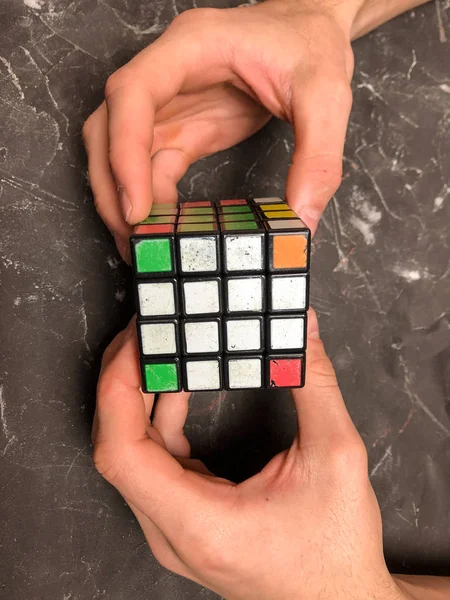 Rubik küpü 3 x 3 erkek eller, yakın çekim, üstten görünüm, mermer arka plan.