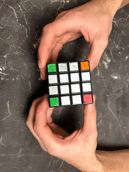 Rubik küpü 3 x 3 erkek eller, yakın çekim, üstten görünüm, mermer arka plan.