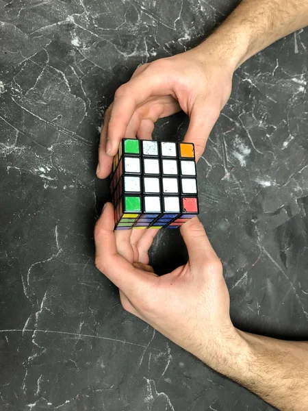 Rubik küpü 3 x 3 erkek eller, yakın çekim, üstten görünüm, mermer arka plan.