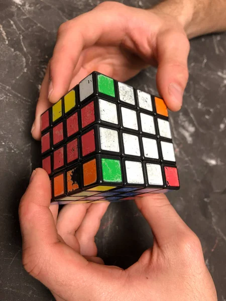 Rubik küpü 3 x 3 erkek eller, yakın çekim, üstten görünüm, mermer arka plan.