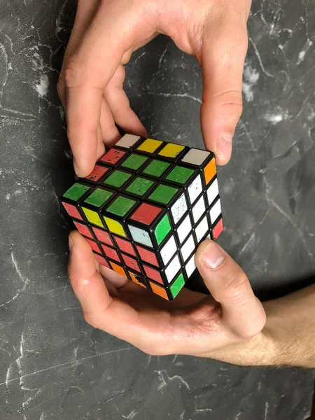 Rubik küpü 3 x 3 erkek eller, yakın çekim, üstten görünüm, mermer arka plan.