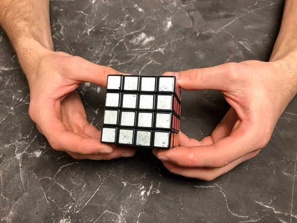 Rubik küpü 3 x 3 erkek eller, yakın çekim, üstten görünüm, mermer arka plan.