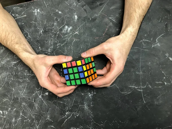 Rubik küpü 3 x 3 erkek eller, yakın çekim, üstten görünüm, mermer arka plan.