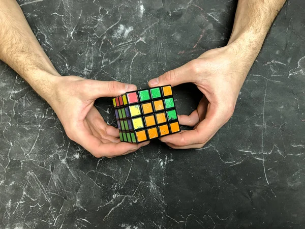 Rubik küpü 3 x 3 erkek eller, yakın çekim, üstten görünüm, mermer arka plan.