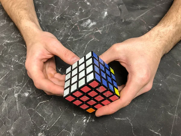 Rubik küpü 3 x 3 erkek eller, yakın çekim, üstten görünüm, mermer arka plan.