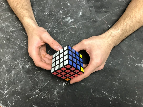 Rubik küpü 3 x 3 erkek eller, yakın çekim, üstten görünüm, mermer arka plan.