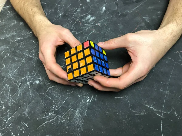 Rubik küpü 3 x 3 erkek eller, yakın çekim, üstten görünüm, mermer arka plan.