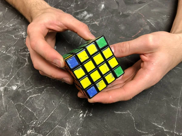 Rubik küpü 3 x 3 erkek eller, yakın çekim, üstten görünüm, mermer arka plan.