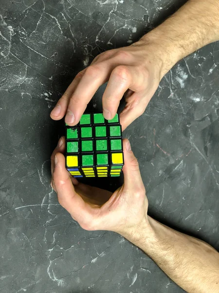 Rubik küpü 3 x 3 erkek eller, yakın çekim, üstten görünüm, mermer arka plan.