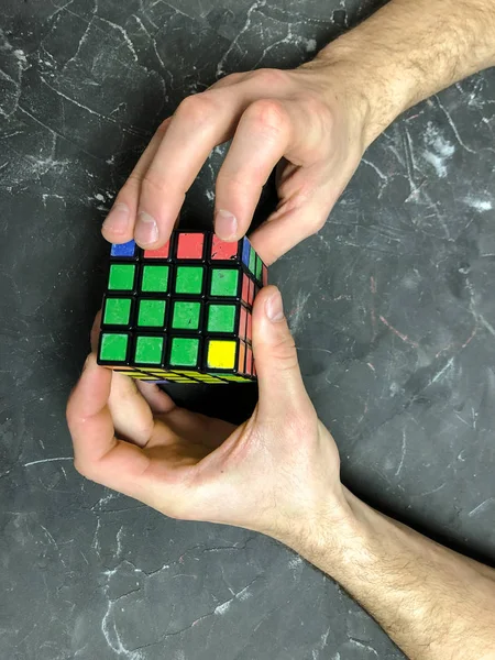 Rubik küpü 3 x 3 erkek eller, yakın çekim, üstten görünüm, mermer arka plan.