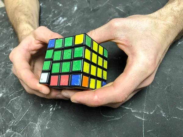 Rubik küpü 3 x 3 erkek eller, yakın çekim, üstten görünüm, mermer arka plan.