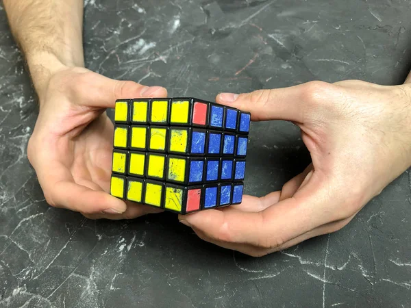 Rubik küpü 3 x 3 erkek eller, yakın çekim, üstten görünüm, mermer arka plan.