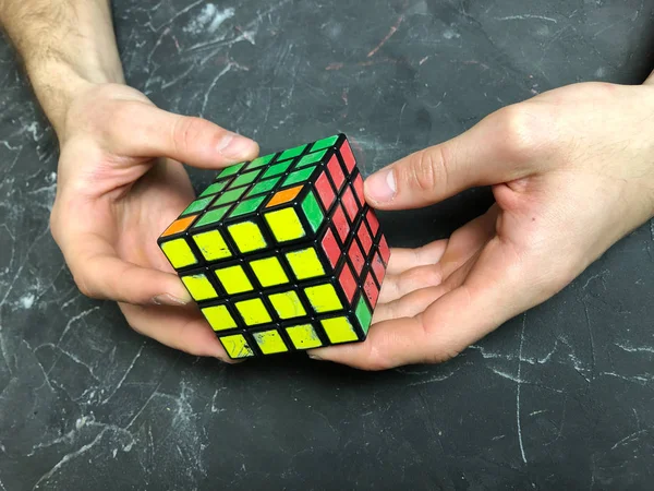 Rubik küpü 3 x 3 erkek eller, yakın çekim, üstten görünüm, mermer arka plan.