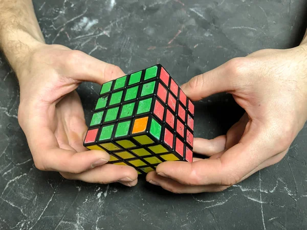 Rubik küpü 3 x 3 erkek eller, yakın çekim, üstten görünüm, mermer arka plan.