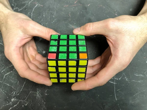 Rubik küpü 3 x 3 erkek eller, yakın çekim, üstten görünüm, mermer arka plan.