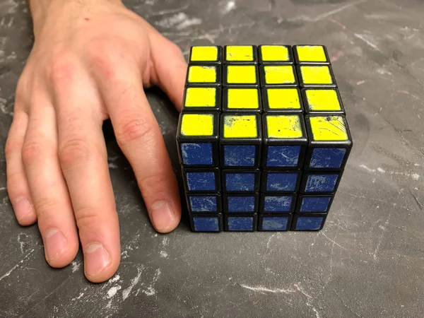 Rubik küpü 3 x 3 erkek eller, yakın çekim, üstten görünüm, mermer arka plan.
