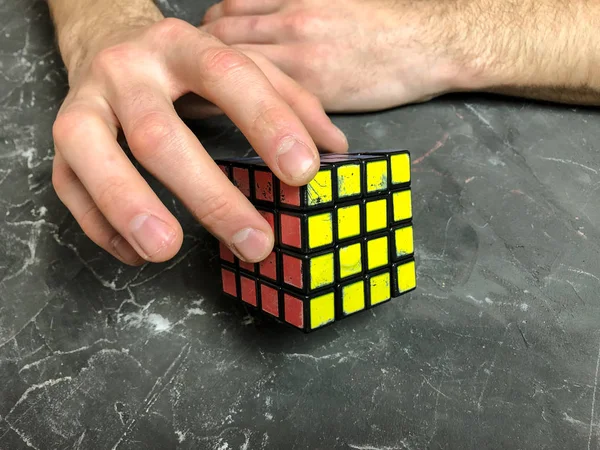 Rubik küpü 3 x 3 erkek eller, yakın çekim, üstten görünüm, mermer arka plan.