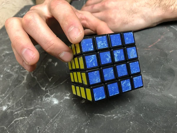 Rubik küpü 3 x 3 erkek eller, yakın çekim, üstten görünüm, mermer arka plan.