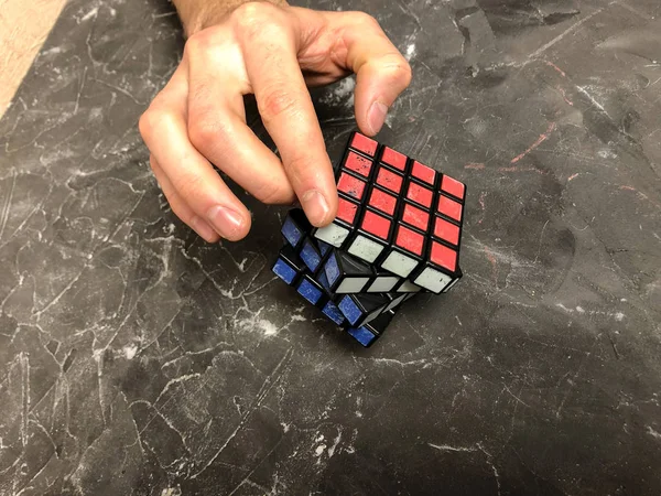 Rubik küpü 3 x 3 erkek eller, yakın çekim, üstten görünüm, mermer arka plan.