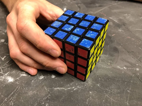 Rubik küpü 3 x 3 erkek eller, yakın çekim, üstten görünüm, mermer arka plan.