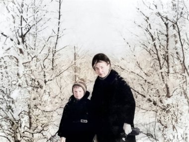 Mutlu anne ve oğulun klasik portresi. Anne oğluna kayak yapmayı öğretiyor. Karlı kış. Retro fotoğraf 1971. SSCB.