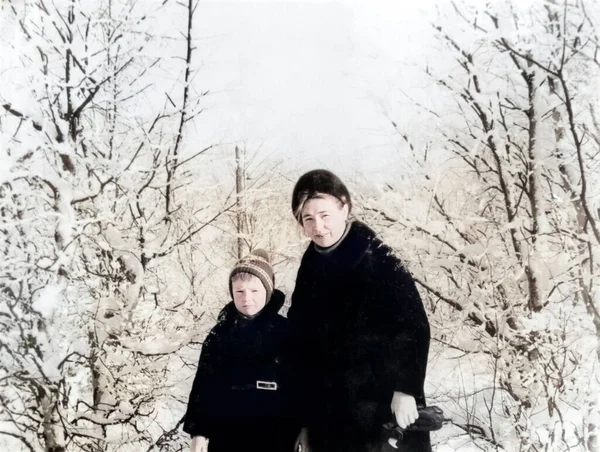 Mutlu anne ve oğulun klasik portresi. Anne oğluna kayak yapmayı öğretiyor. Karlı kış. Retro fotoğraf 1971. SSCB.