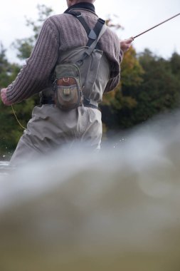 cropped view of man fishing at river during autumn season  clipart