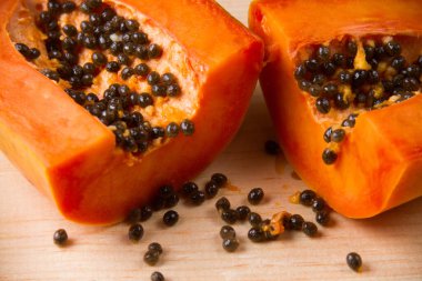 Olgun papaya meyvesi yarısı ahşap masada.