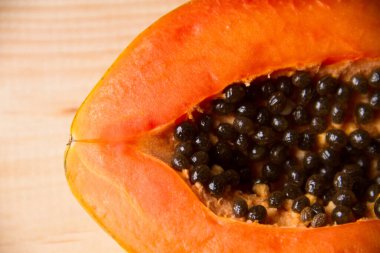 Olgun papaya meyvesi yarısı ahşap masada.