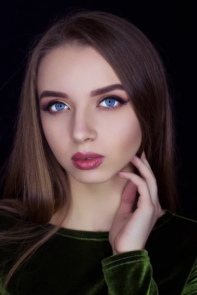 Young beautiful showy girl with luxurious wavy shiny hair looks into the frame. Brown-haired, blue eyes, big red lips. A large portrait. Fashion, beauty, care, health. Salon.Beautiful long hair.